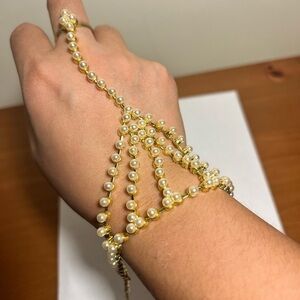 Hand thong harness bracelet with ring style pearl and gold design